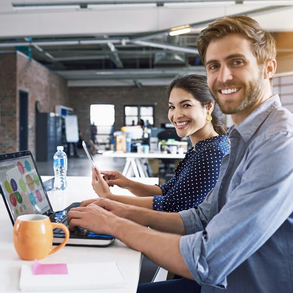 Dos personas trabajando juntas frente a una computadora en una oficina